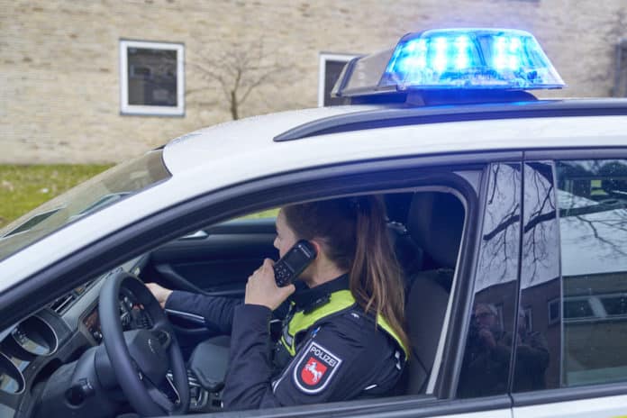 Polizeifahrzeug mit telefonierender Polizistin - Symbolfoto für Polizeieinsatz