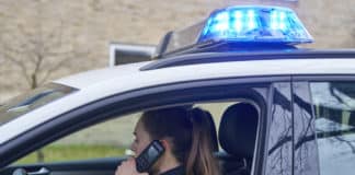 Polizistin telefoniert im Polizeifahrzeug - Symbolfoto für einen Polizeieinsatz