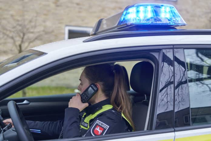 Polizistin telefoniert im Polizeifahrzeug - Symbolfoto für einen Polizeieinsatz